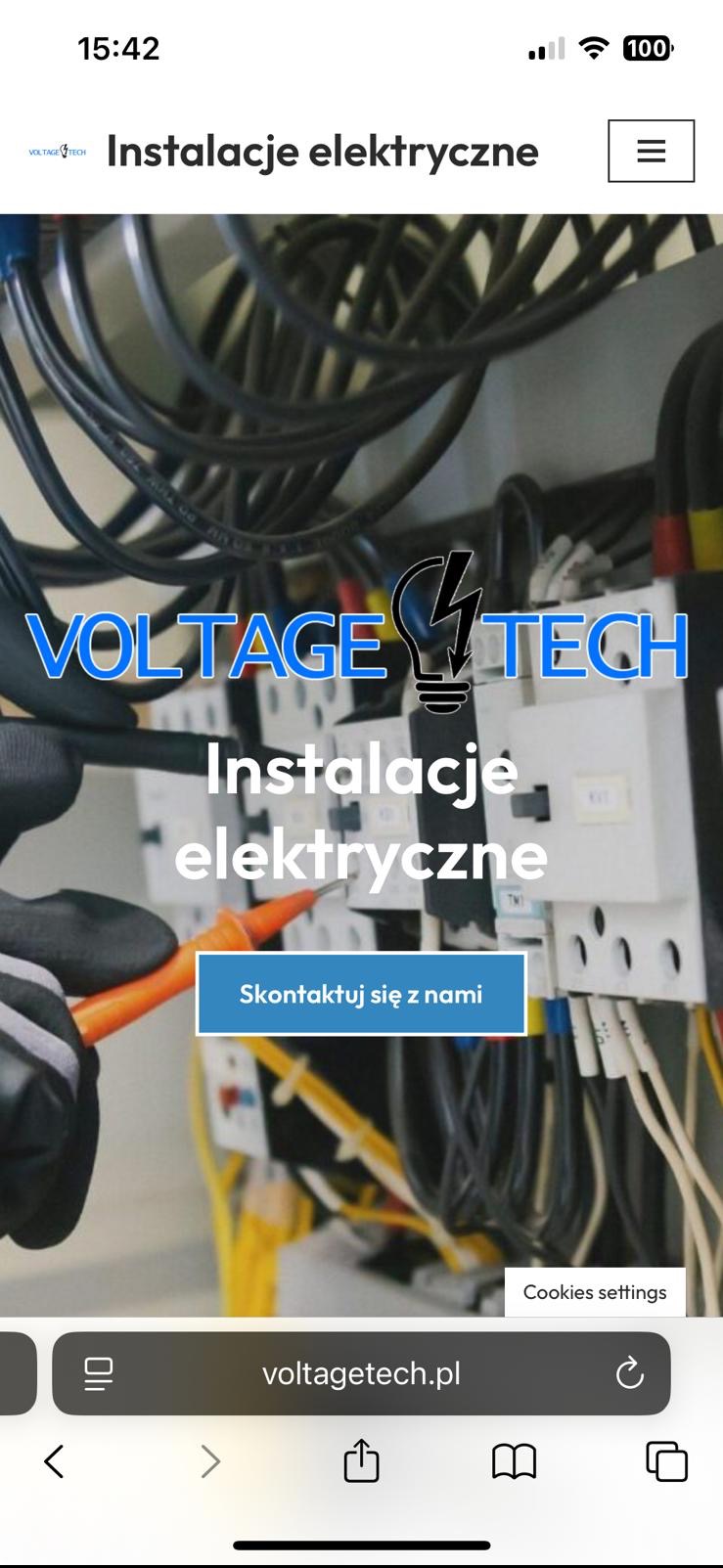 Instalacje elektryczne: widok na panel sterowania z przewodami, testowany przez elektryka w rękawicach, z nazwą firmy Voltage Tech na ekranie telefonu.