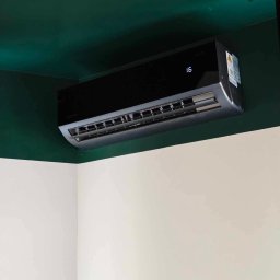 AllinClima Marek Gąsiorowski - Czarny klimatyzator Rotenso z cyfrą 16 na wyświetlaczu, zamontowany na ścianie, gdzie górna część jest zielona, a dolna biała.