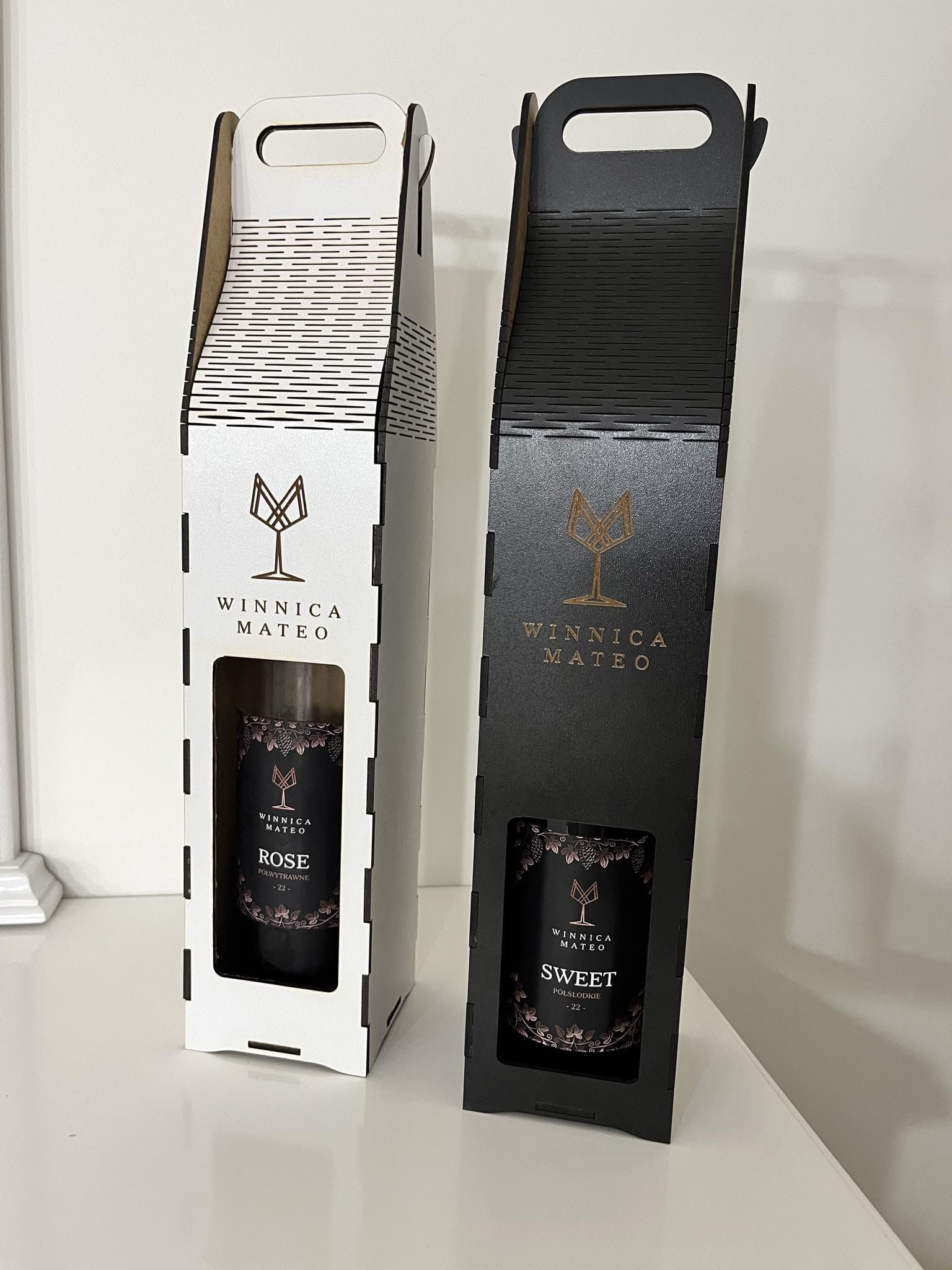 Eleganckie, laserowo wycinane opakowania na wino w kolorach bieli i czerni, z logo Winnica Mateo i okienkiem prezentującym etykietę wina.