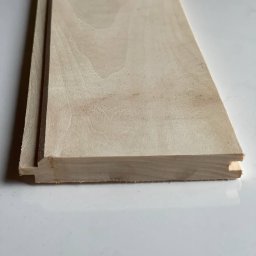 Artorix - Profilowana deska podłogowa z jasnego drewna, widok z bliska na łączenie wpust-wypust. Widoczne słoje drewna i precyzyjne wykończenie.