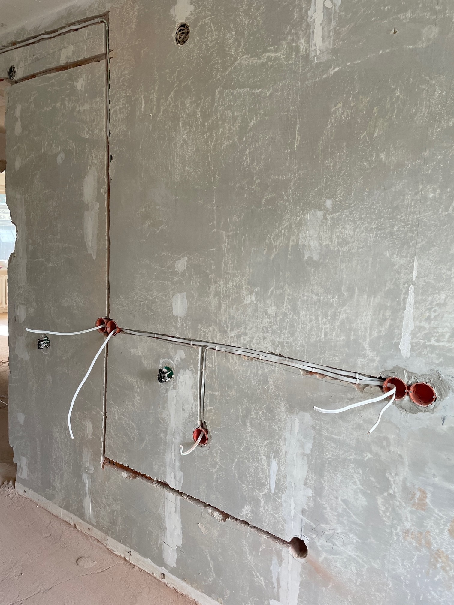 Ściana w trakcie prac wykończeniowych w Opolu: widoczne przewody elektryczne w peszlach, puszki instalacyjne i surowa powierzchnia przygotowana pod gładzie.