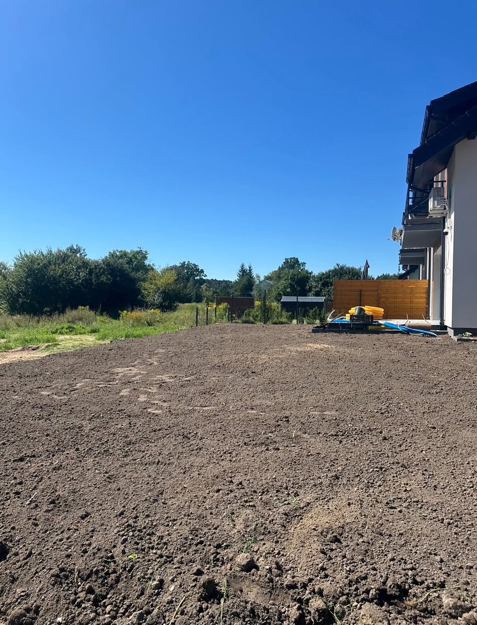 Rozkładanie przesianej ziemi pod trawnik.