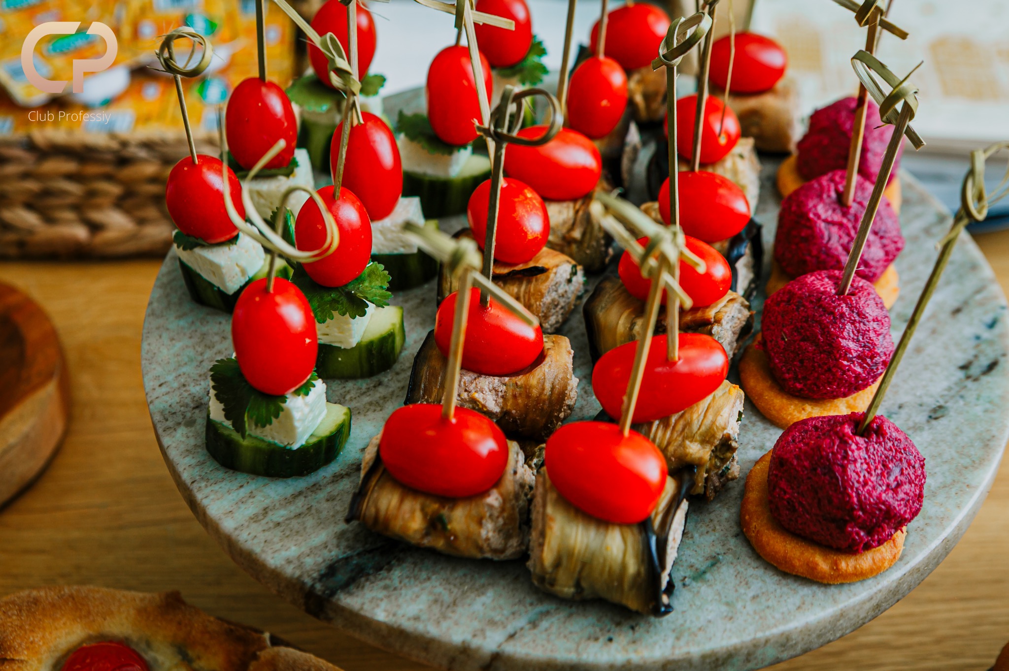 Elegancki catering: kolorowe koreczki z pomidorkami cherry, bakłażanem i buraczkami na marmurowej tacy, idealne na przyjęcie firmowe lub świąteczne.