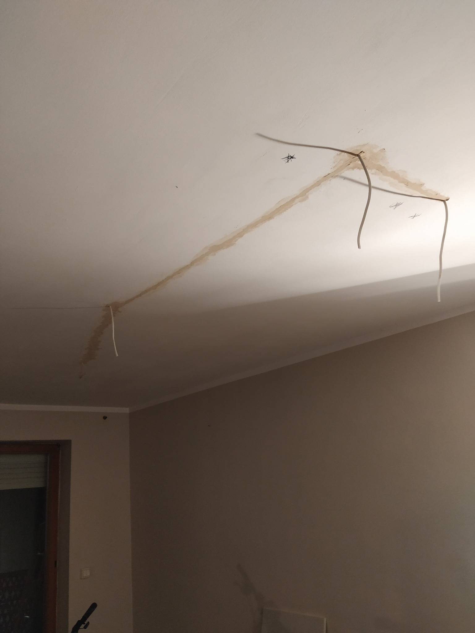 Biały sufit z widocznymi śladami po instalacji elektrycznej i przewodami. Przygotowanie do prac wykończeniowych, widoczne niedoskonałości i ślady po montażu.