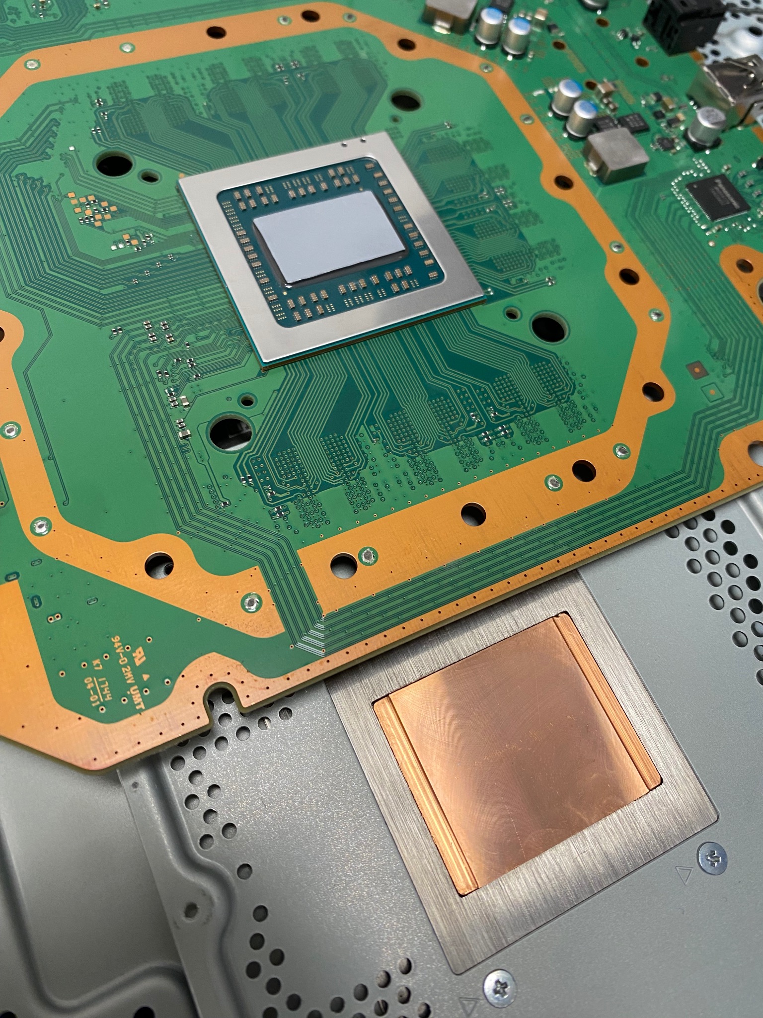 Otwarta obudowa konsoli z widoczną płytą główną i procesorem z radiatorem, ukazująca skomplikowaną konstrukcję wewnętrzną urządzenia.