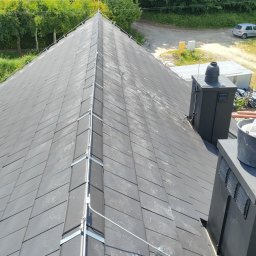 SOLID INSTAL - Szary dach z dachówki ceramicznej z zamontowaną instalacją odgromową, widok z góry, na tle zieleni i zabudowań.