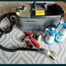 Profesjonalny odkurzacz piorący Karcher Puzzi 10/1 z akcesoriami na dywanie w geometryczne wzory. Widoczne szczotki i spryskiwacze.