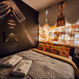 MG PROJEKT GRZEGORZ RADTKE - Sypialnia z ciemną ścianą z muralem, łóżkiem i ścianą z cegieł solnych z dekoracjami. Unikalny wystrój wnętrza z akcentem artystycznym i relaksacyjnym.