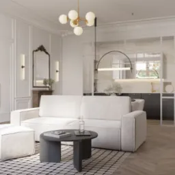 Elegancki salon z sofą w odcieniach bieli, stolikiem kawowym i otwartą kuchnią z marmurowym blatem. Klasyczne sztukaterie zdobią ściany.