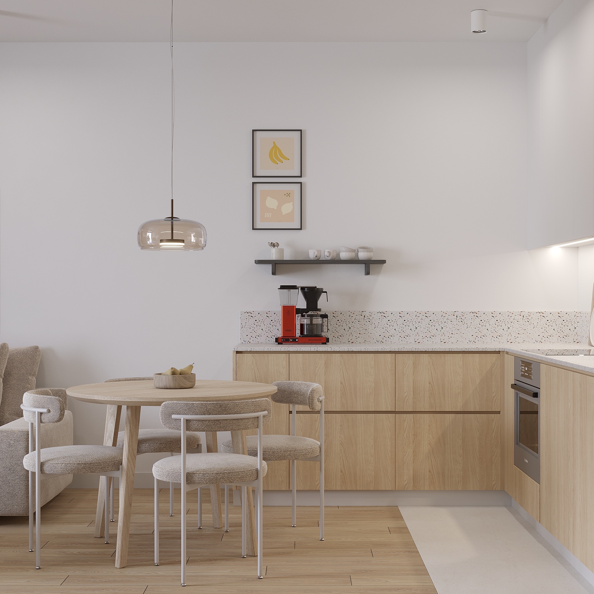 Jasna kuchnia z drewnianymi frontami, okrągłym stołem i designerskim oświetleniem. Na ścianie grafiki z motywami owoców i półka z naczyniami.