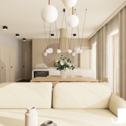 JAKUB SZELĄG PROJEKTOWANIE WNĘTRZ - Jasne wnętrze: sofa, stół z kwiatami, schody z drewnianymi stopniami i szklaną balustradą. Nad stołem wiszą lampy w kształcie kul. Stonowana kolorystyka.