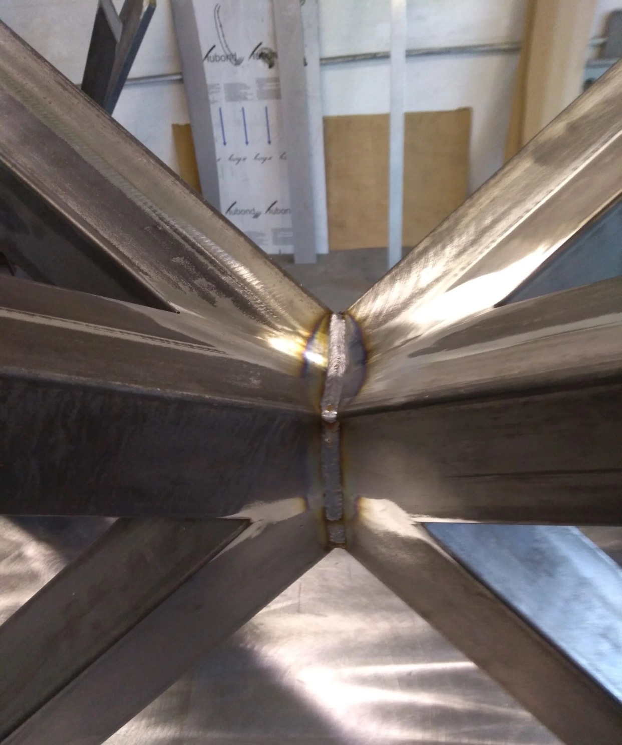 Węzeł konstrukcyjny zespawanych, metalowych profili. Widoczne spoiny i ślady obróbki. Surowy metal w industrialnym stylu, detal konstrukcyjny.