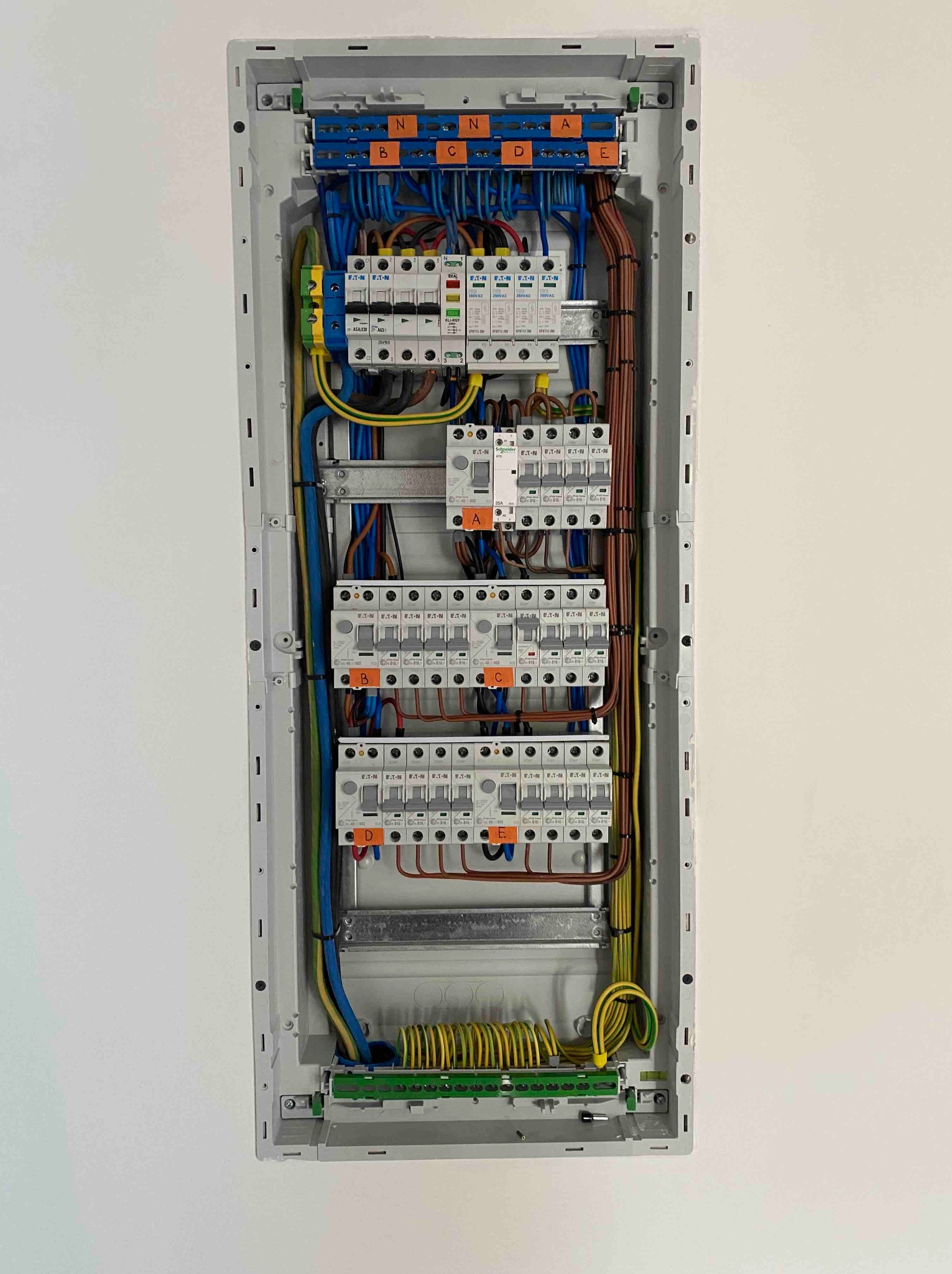 Rozdzielnica elektryczna z bezpiecznikami i okablowaniem, widok z góry. Przewody oznaczone kolorami i etykietami. Nowoczesna instalacja w obudowie.
