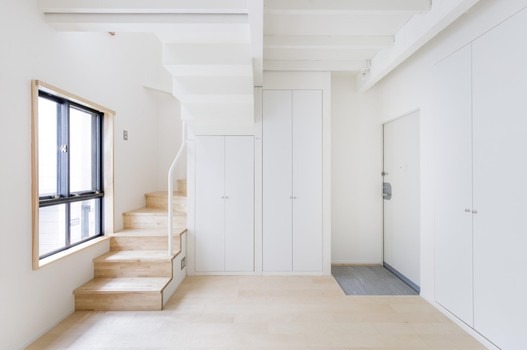 Jasne, minimalistyczne wnętrze z drewnianymi schodami i białymi szafami w Gernsbach. Widoczne okno i drzwi. Styl skandynawski, czyste linie.