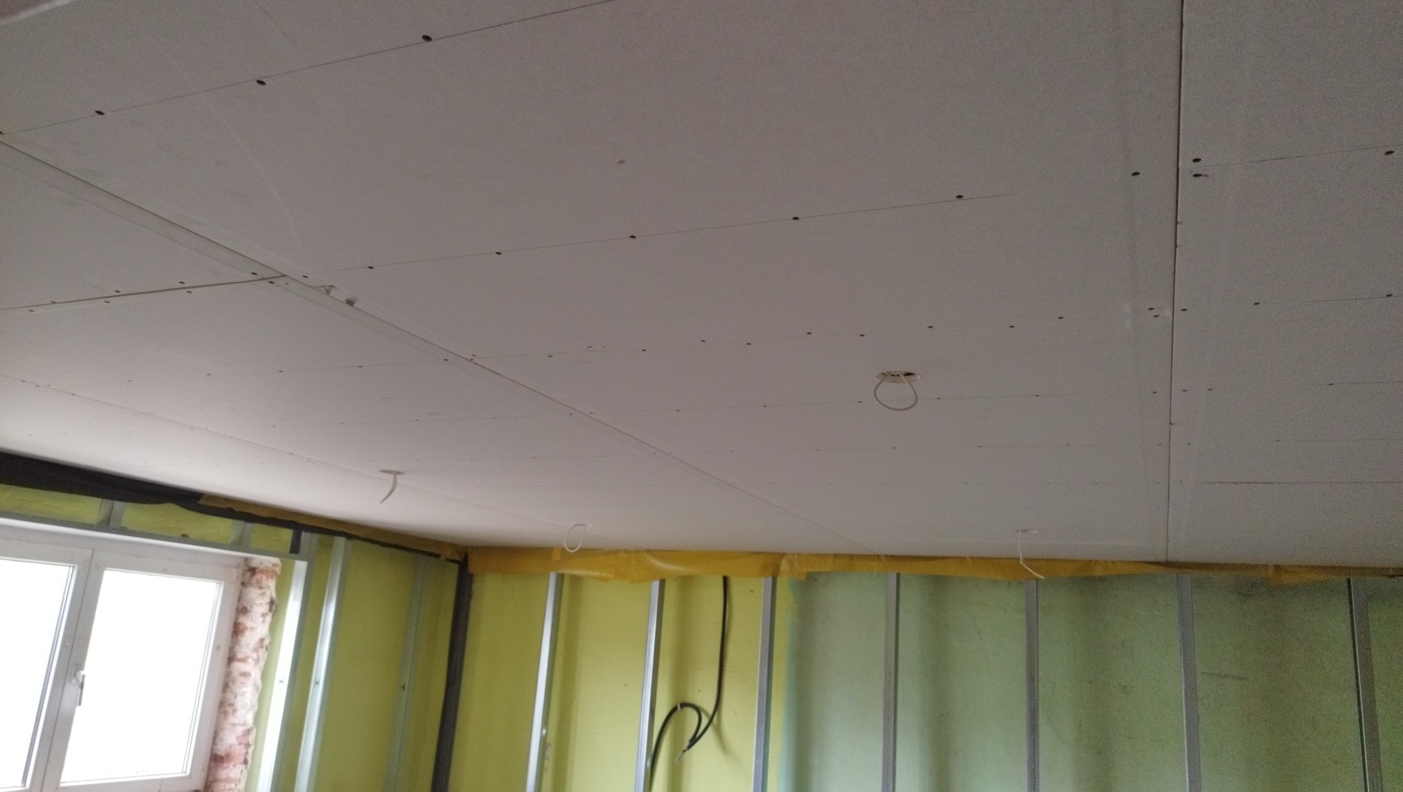 Zamontowane płyty gipsowo-kartonowe na suficie, widoczne profile i instalacja elektryczna. Ściany z izolacją i profilem.