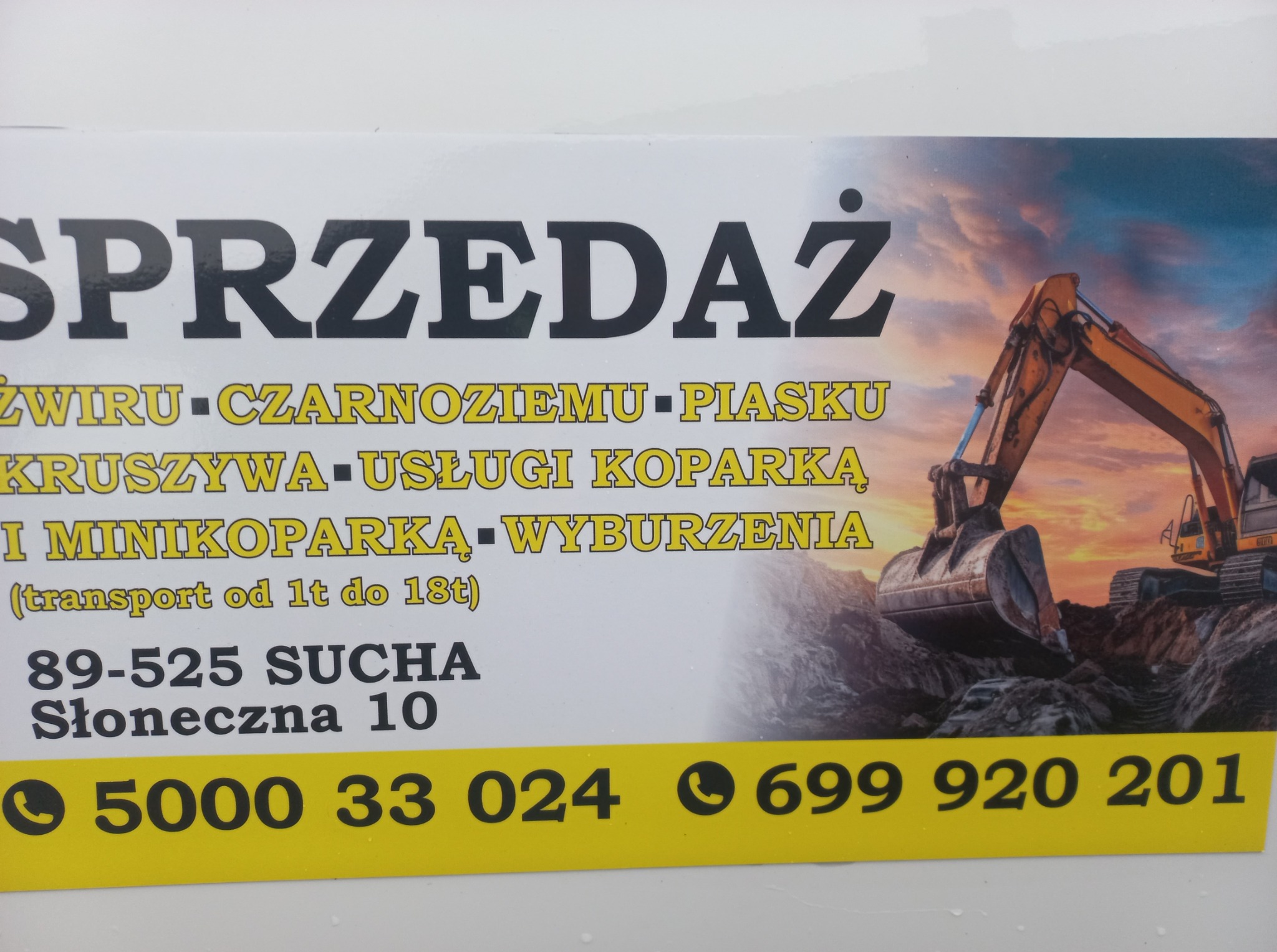 Ogłoszenie: Sprzedaż żwiru, piasku, usługi koparką i wyburzenia. Adres: Sucha, Słoneczna 10. Numery telefonu: 5000 33 024, 699 920 201. Grafika koparki w tle.