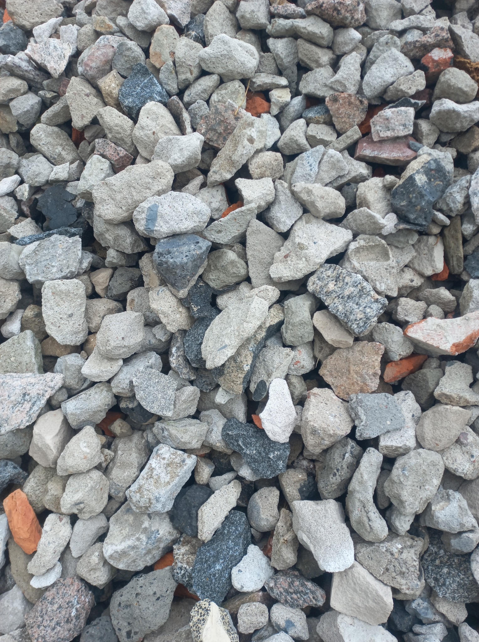 Stos gruzu budowlanego w Sucha Beskidzka. Różne odcienie szarości i beżu, fragmenty cegieł. Materiał do utwardzania terenu lub podłoża.