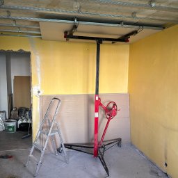 Marcin Zalewski - Żółty pokój w trakcie montażu sufitu podwieszanego z płyt gipsowo-kartonowych. Widoczny podnośnik do płyt i drabina. Częściowo wykończone ściany.