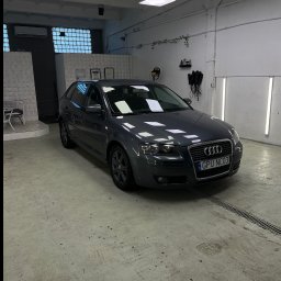 Filo Autokosmetyka - Szary Audi A3 po myciu w jasnym garażu z kratką ściekową w podłodze, widoczne oświetlenie sufitowe i narzędzia na ścianie. Tablica rejestracyjna GPU NC03.