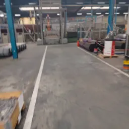 Wnętrze hali produkcyjnej z metalowymi elementami i konstrukcjami. Widoczne rury, profile i maszyny do obróbki metali. Oświetlenie przemysłowe.