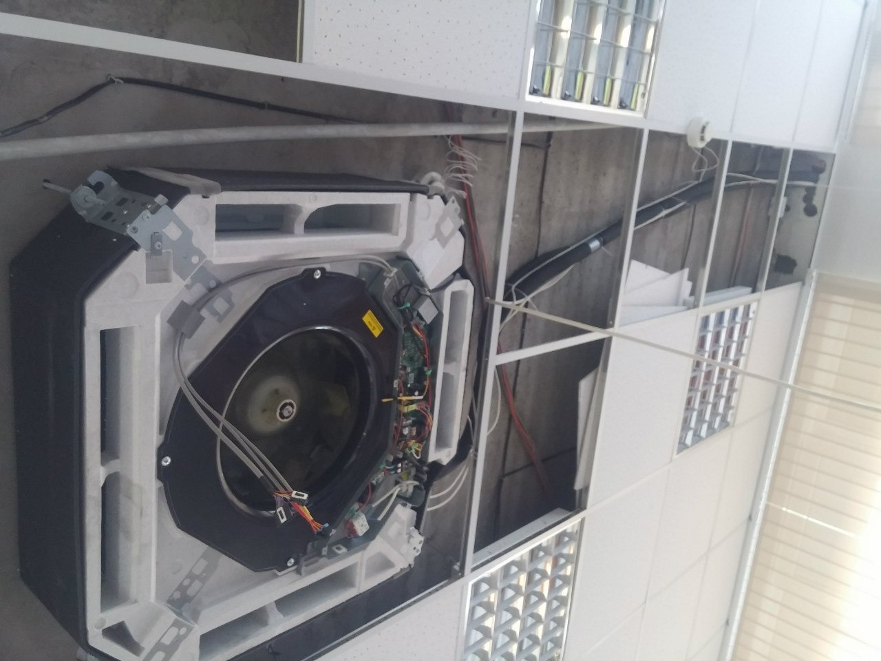 Kasetonowa klimatyzacja sufitowa w trakcie montażu, widoczne elementy instalacji i podwieszany sufit. Ujęcie z dołu, perspektywa podkreśla etap prac.