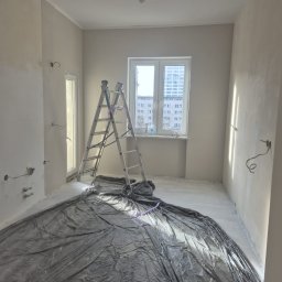 SHIPSTEEL MATEUSZ SKOPIŃSKI - Pokój w trakcie przygotowania do malowania: zabezpieczona folią podłoga, drabina oparta o ścianę, ściany częściowo zagruntowane, widoczne wyprowadzenia instalacji elektrycznej.