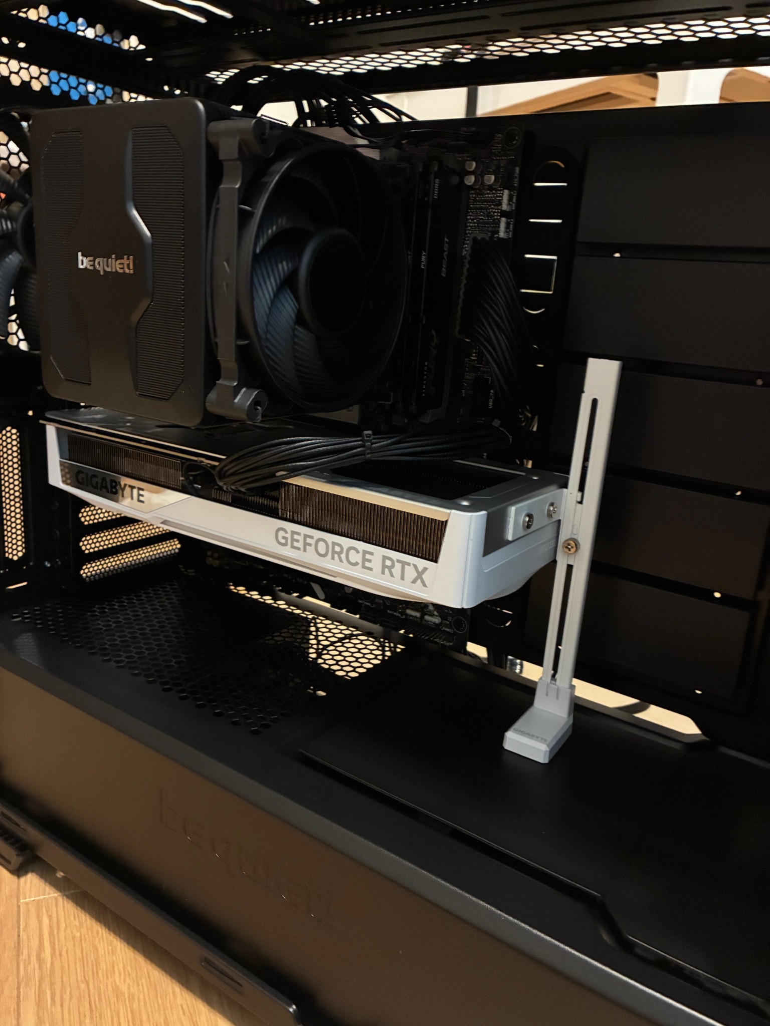 Wnętrze obudowy PC z kartą graficzną Gigabyte GeForce RTX i chłodzeniem be quiet!. Widoczne kable i komponenty na płycie głównej. Stabilizator karty graficznej.