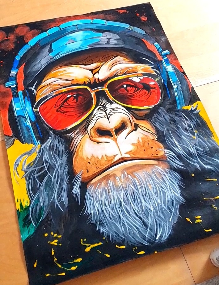 Kolorowy portret goryla w słuchawkach i okularach na czarnym tle z plamami farby, namalowany na płótnie. Nietypowe połączenie realizmu i abstrakcji.