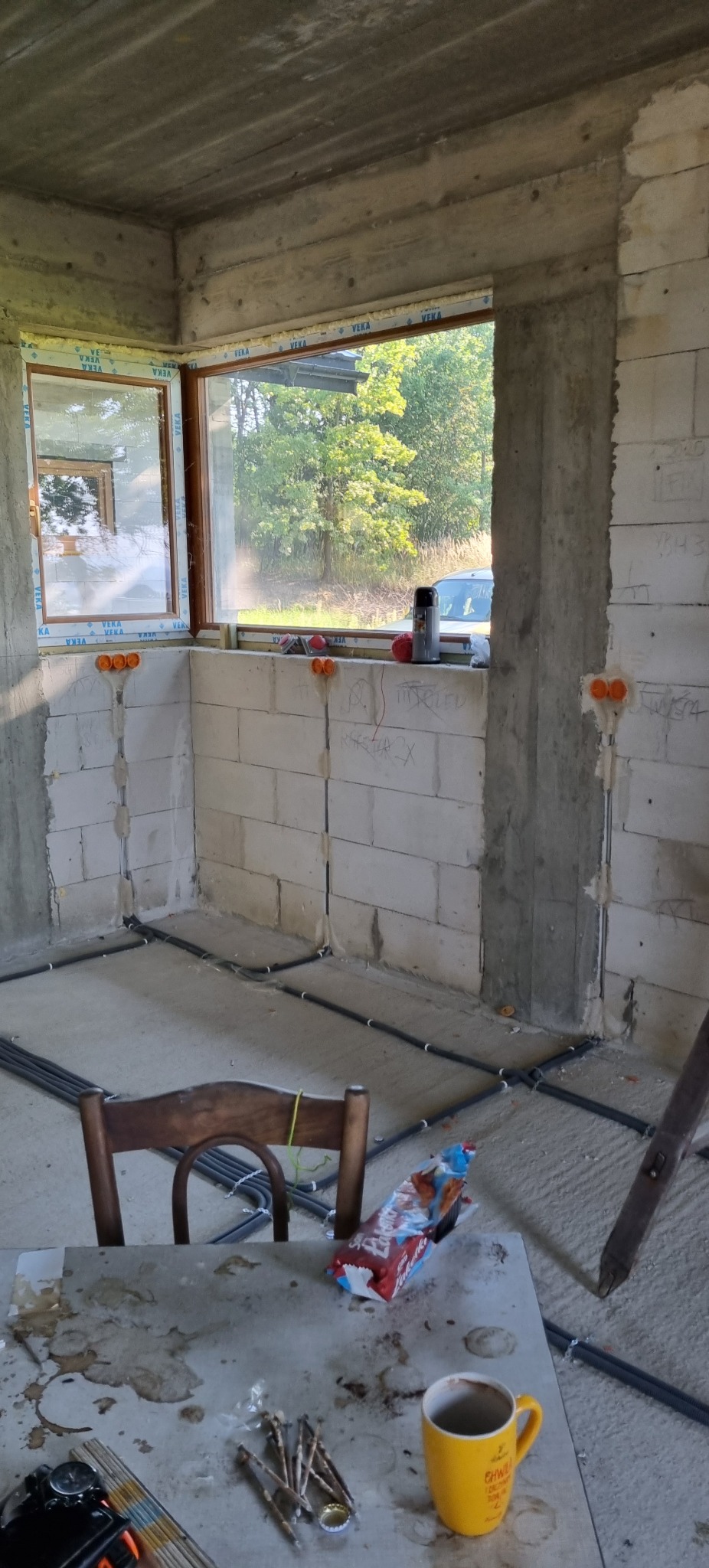 Instalacja elektryczna w surowym wnętrzu w Osobnicy. Widoczne kable prowadzone po podłodze i puszki elektryczne w ścianach z betonu komórkowego.