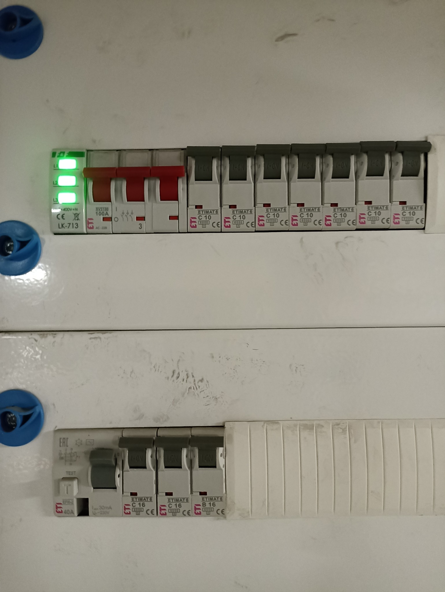 Rozdzielnica elektryczna z bezpiecznikami ETIMAT, część z nich w pozycji 'ON', część wyłączona. Widoczne diody sygnalizacyjne i oznaczenia parametrów.