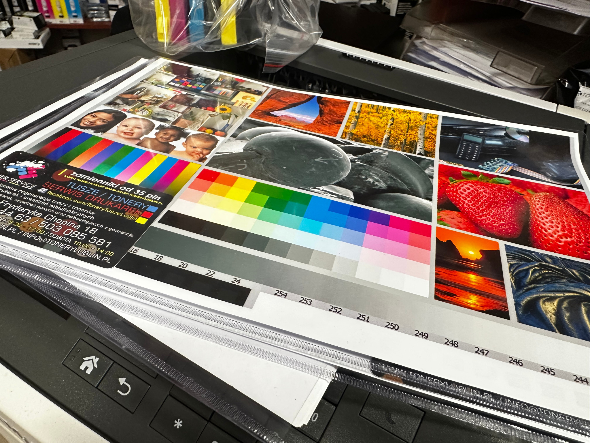 Test wydruku kolorów na drukarce, widoczne zdjęcia i paleta barw. Na pierwszym planie panel sterowania drukarki. Reklama serwisu tuszy i tonerów.
