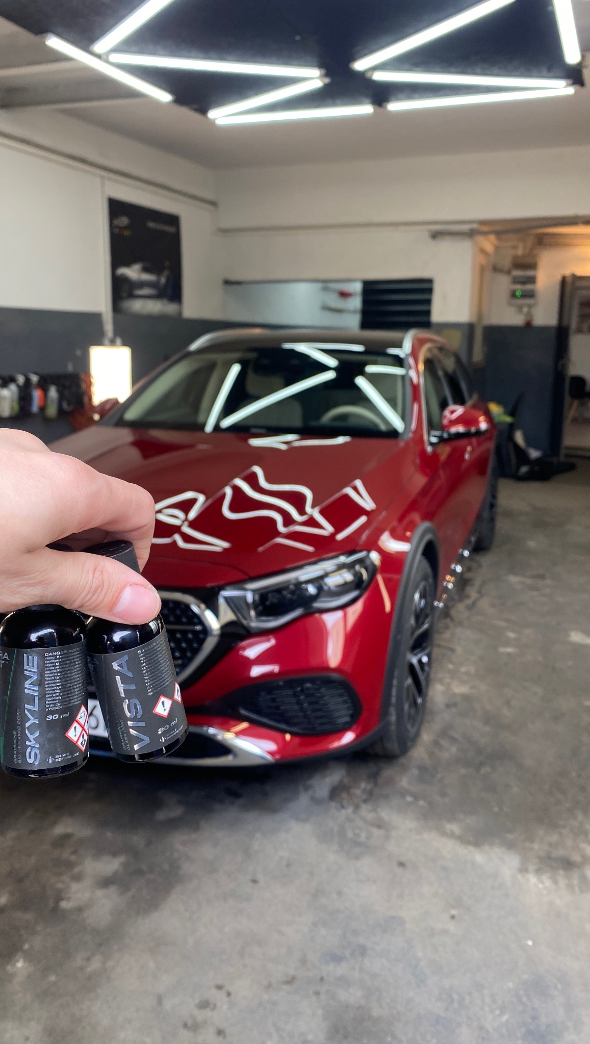 Czerwony samochód po aplikacji powłoki ceramicznej, z widocznymi buteleczkami Skyline i Vista w dłoni. Detailing w dobrze oświetlonym garażu.