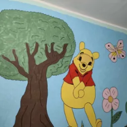 Pokój dziecięcy z ręcznie malowaną ścianą: Kubuś Puchatek, drzewo, motyl i Prosiaczek na tle błękitnego nieba. Artystyczne malowanie ścian w pokoju dziecka.