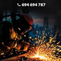 Spawacz w hełmie ochronnym, iskry podczas spawania, reklama usług spawalniczych z numerem telefonu i adresem e-mail.