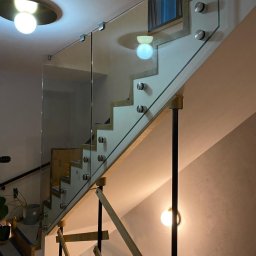 Ases sp zoo - Nowoczesne schody z balustradą szklaną, mocowaną punktowo. Realizacja z Góry Kalwarii. Widoczne oświetlenie schodowe i elementy konstrukcyjne.