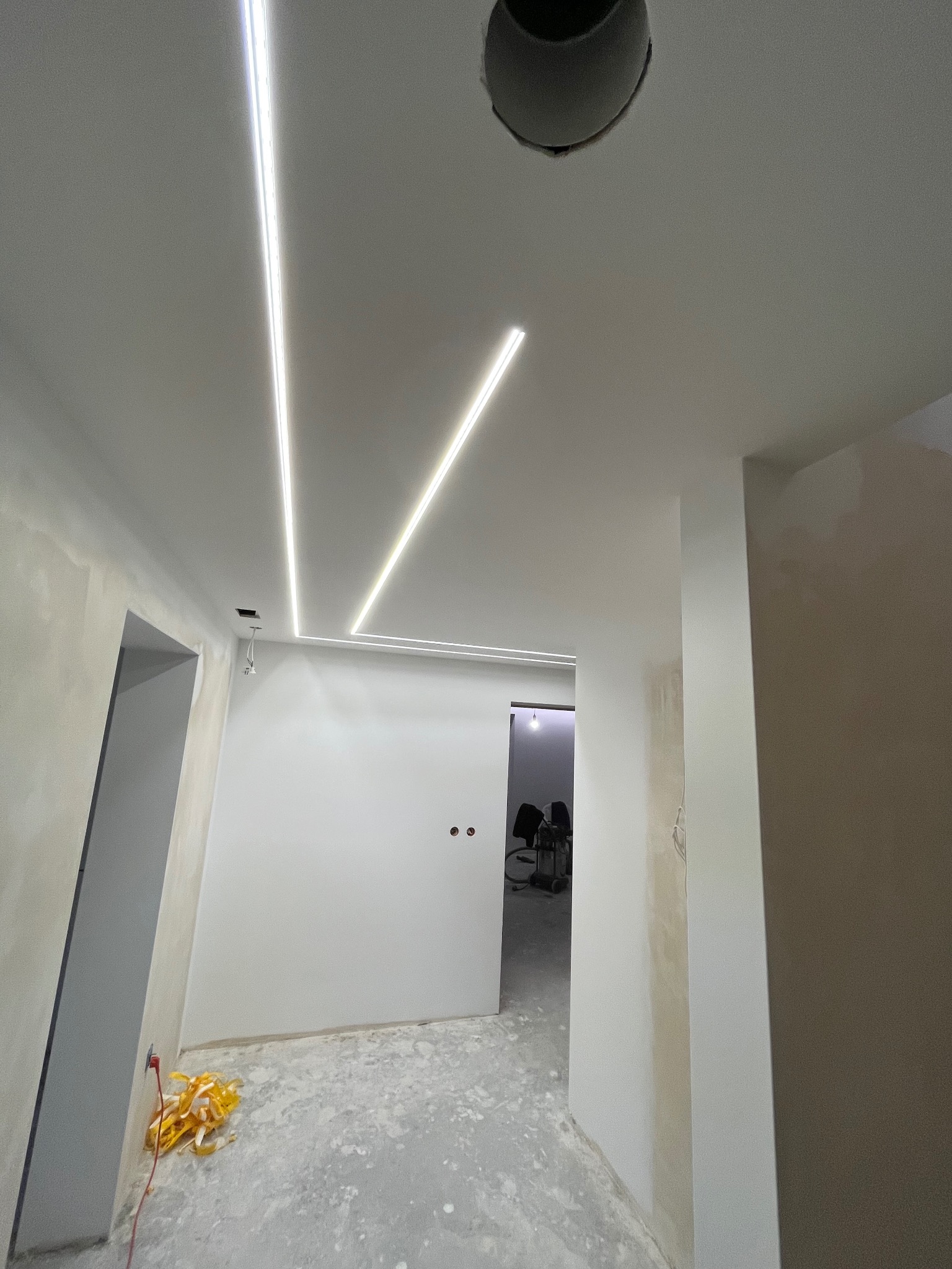 Nowoczesne oświetlenie LED w suficie podwieszanym w korytarzu podczas wykańczania wnętrz. Widoczne przewody i otwór na punktowe źródło światła.
