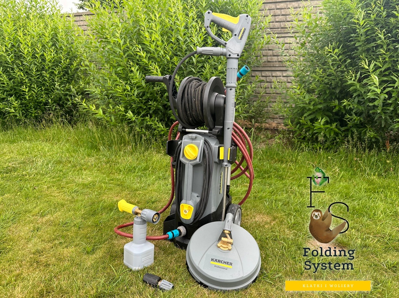 Profesjonalna myjka ciśnieniowa Kärcher z akcesoriami na trawie, gotowa do mycia kostki brukowej. W tle zielona roślinność.