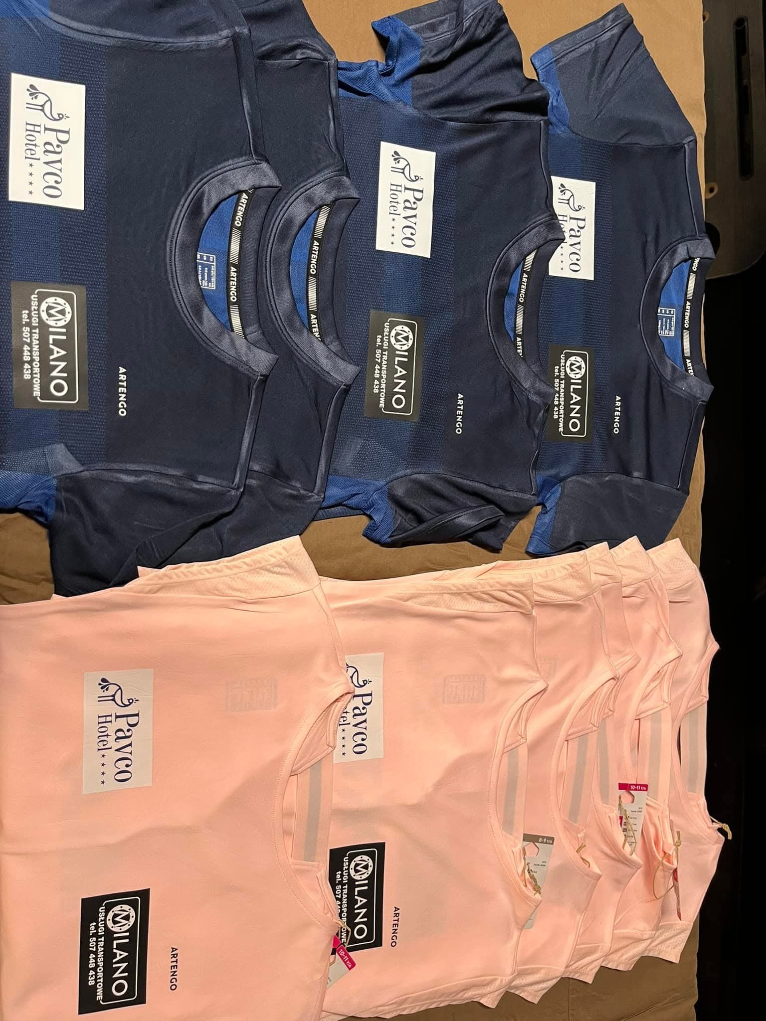 Rząd niebieskich i różowych koszulek sportowych z nadrukowanymi logo firmowymi, leżących na brązowym tle. Widoczne metki i zbliżenie na nadruki.