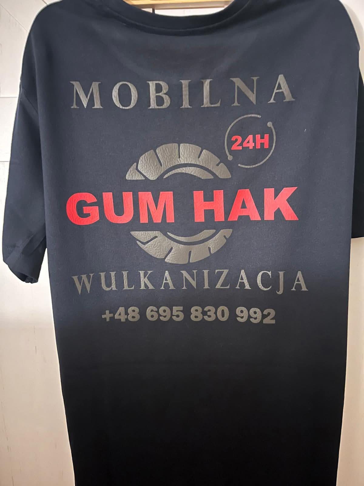 Czarna koszulka z szarym nadrukiem: 'Mobilna GUM HAK Wulkanizacja 24H' i numerem telefonu. Grafika opony. Odzież robocza.