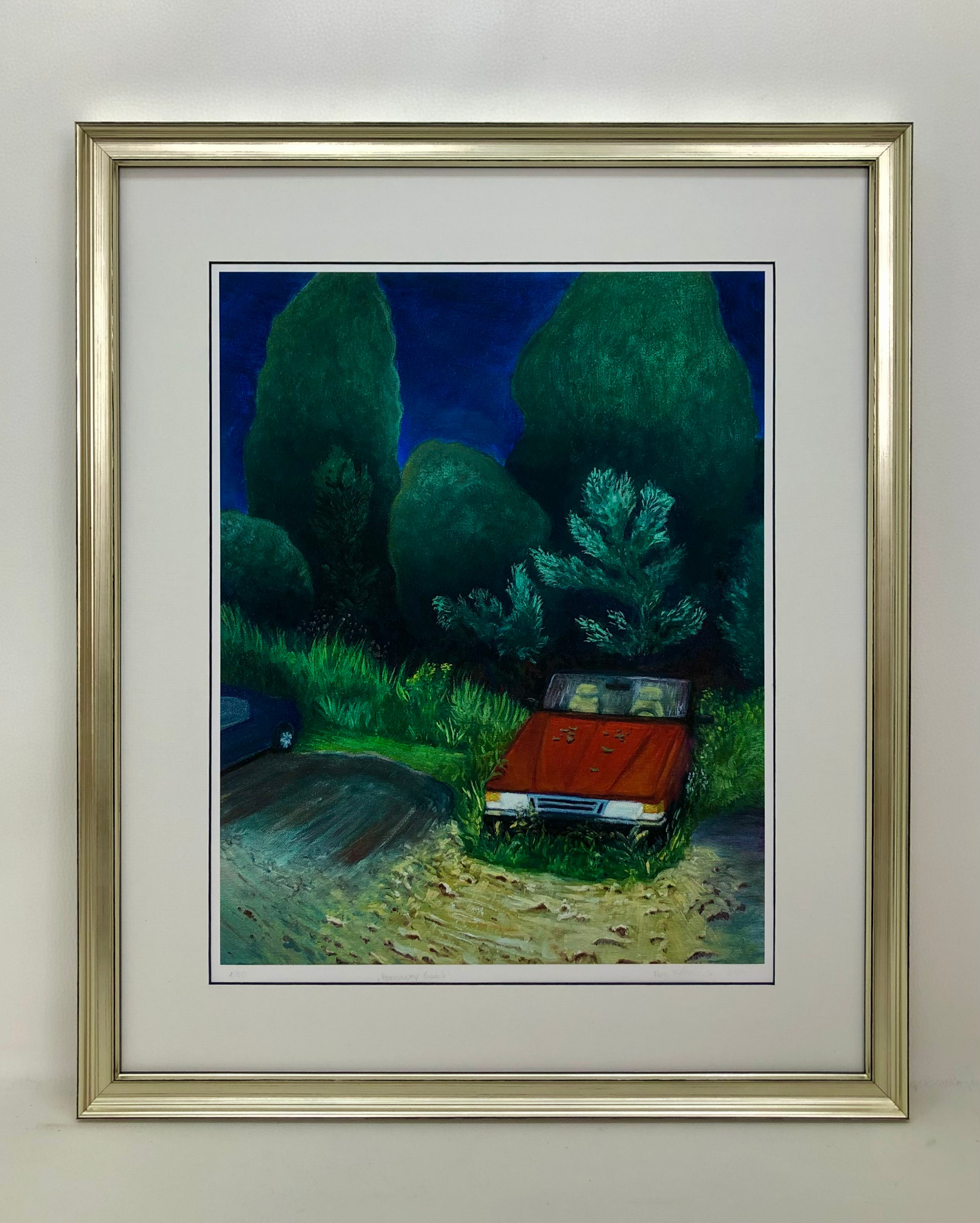 Oprawiony w złotą ramę, sygnowany print artystyczny przedstawia nocny krajobraz z czerwonym samochodem na tle zieleni i drzew. Passe-partout i szyba podkreślają dzieło.
