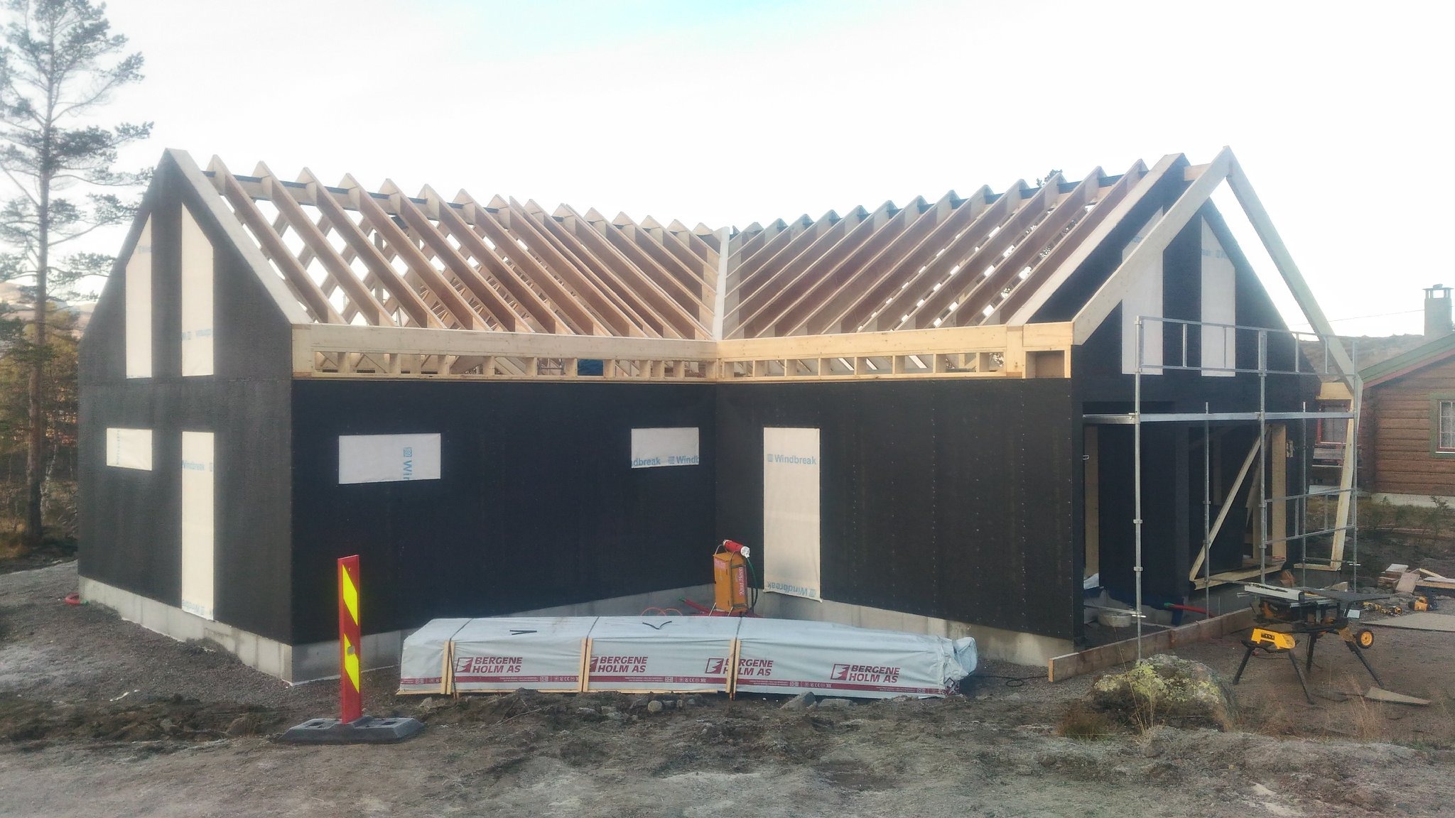 Konstrukcja domu szkieletowego w Cekcynie na etapie montażu więźby dachowej. Widoczne materiały budowlane i rusztowanie.