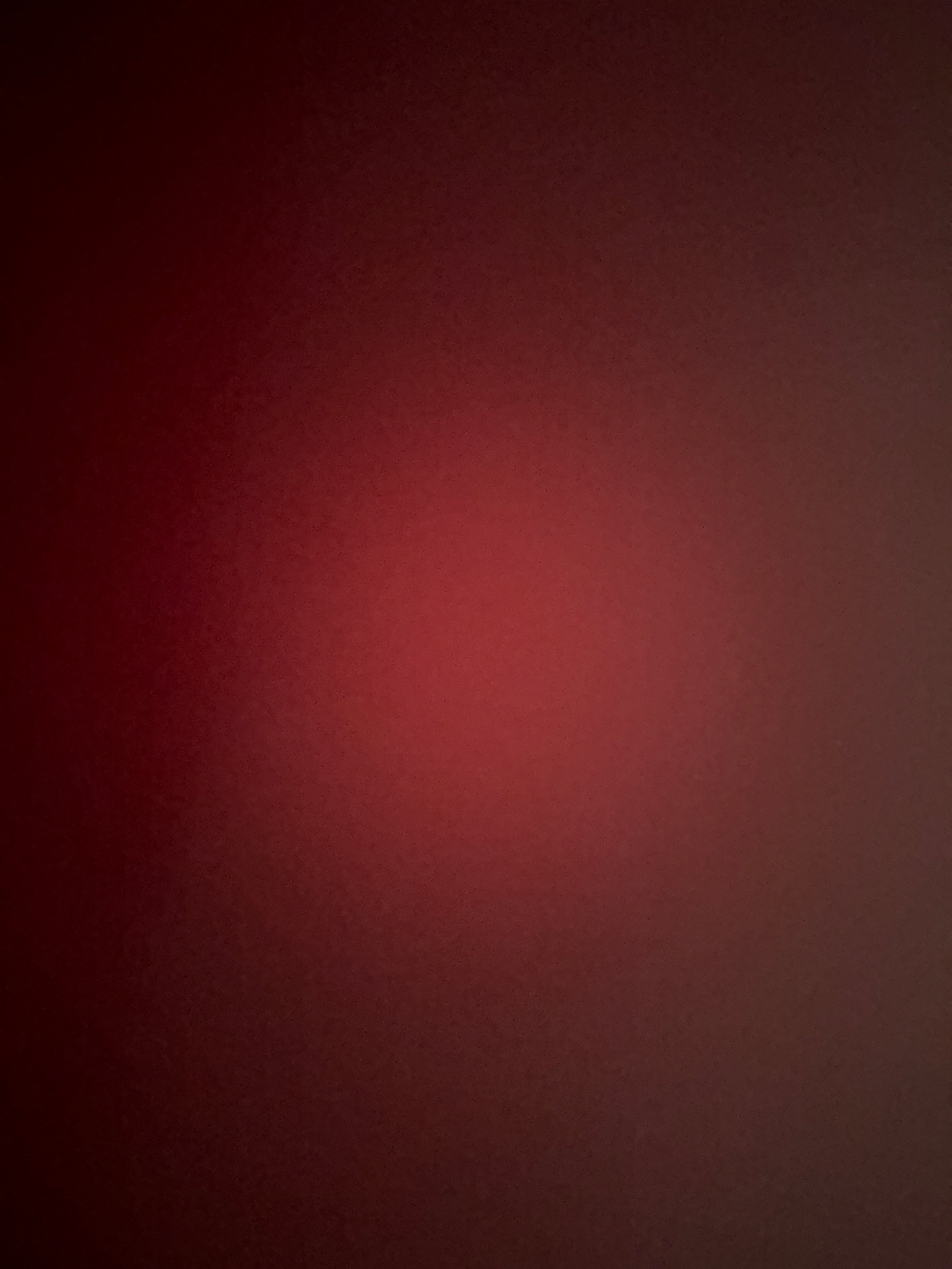 Ciemnoczerwona ściana z subtelnym gradientem, od jaśniejszego odcienia w centrum do ciemniejszego na obrzeżach. Delikatna tekstura powierzchni.