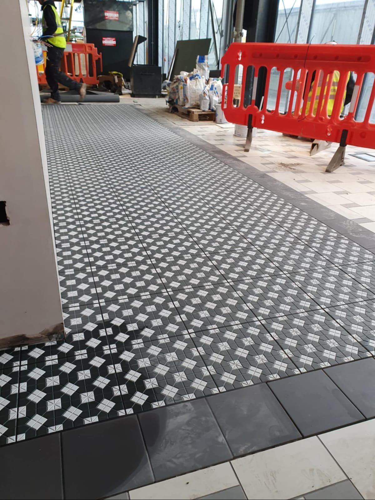 Ukończone układanie wzorzystej, czarno-białej podłogi z płytek w Lubsku. Widoczne detale wykończenia i wzór płytek. Praca glazurnicza.