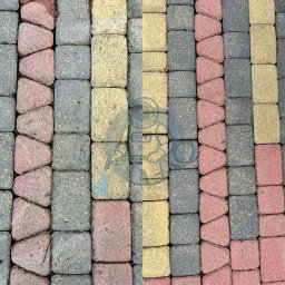 Shiny Space - mycie ciśnieniowe - Kolorowa kostka brukowa ułożona w rzędach, widok z góry. Różne odcienie szarości, żółci i czerwieni tworzą geometryczny wzór na powierzchni chodnika.