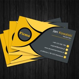 Grafmaga - Stos wizytówek w odcieniach żółci i szarości na ciemnym tle imitującym drewno. Wizytówka z imieniem Jan Kowalski i danymi kontaktowymi.