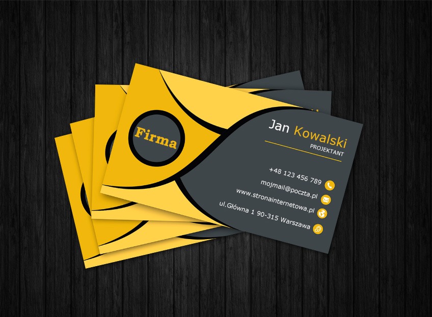 Stos wizytówek w odcieniach żółci i szarości na ciemnym tle imitującym drewno. Wizytówka z imieniem Jan Kowalski i danymi kontaktowymi.