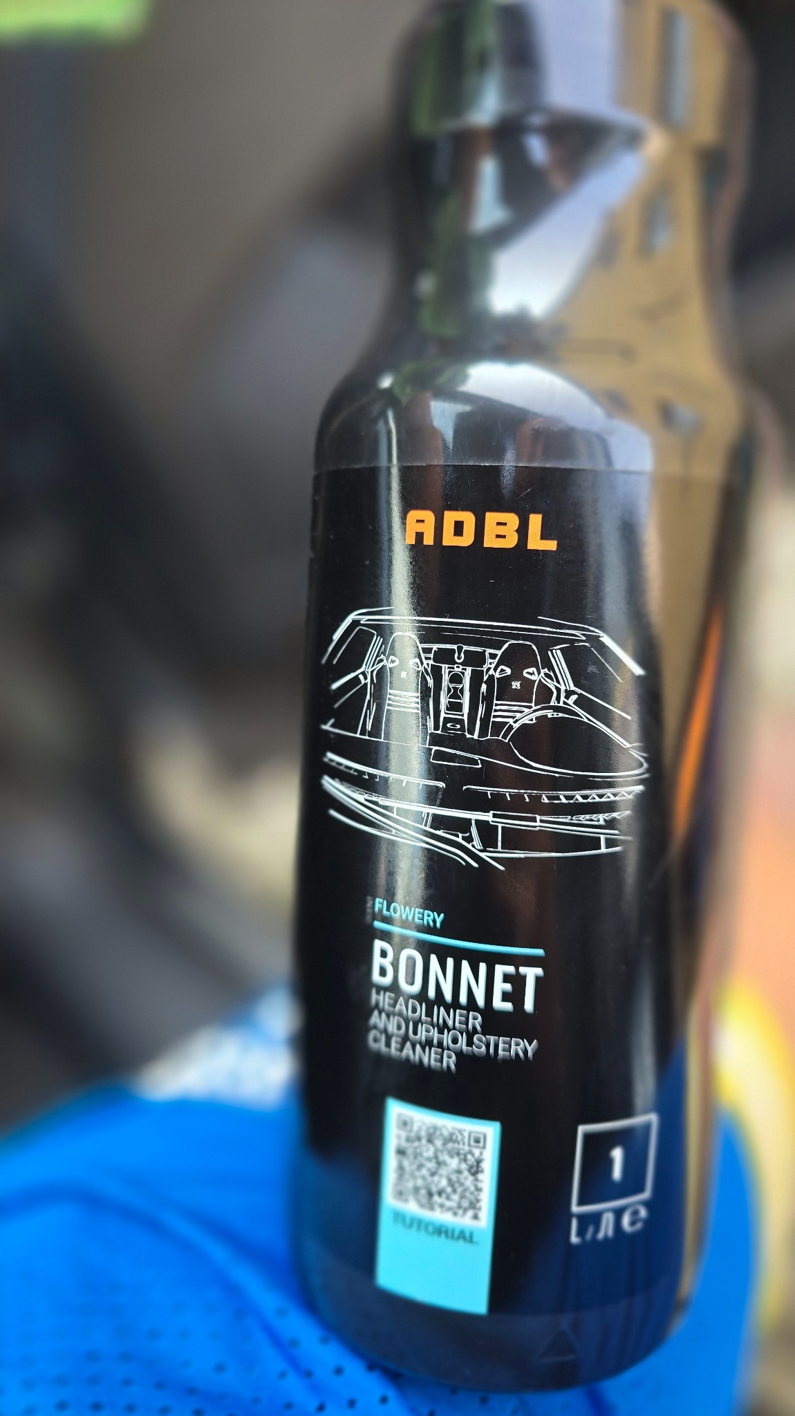Butelka środka ADBL Bonnet do czyszczenia podsufitki i tapicerki samochodowej. Na etykiecie schemat wnętrza auta i kod QR do tutorialu.