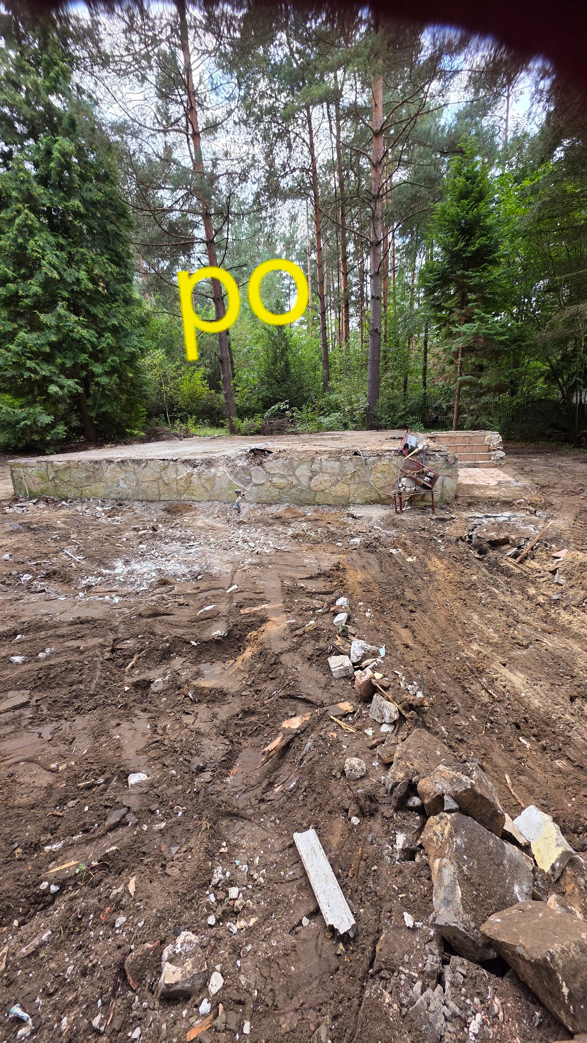 Zdjęcie 'po' rozbiórce fundamentów budynku w lesie. Widoczne resztki fundamentów i gruz na ziemi. Teren przygotowany pod nową budowę.