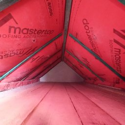 RPGO SPÓŁKA Z OGRANICZONĄ ODPOWIEDZIALNOŚCIĄ - Ocieplenie poddasza wełną mineralną, widok od wewnątrz. Czerwona folia paroizolacyjna Mastertop i drewniana konstrukcja dachu. Izolacja na podłodze poddasza.