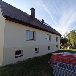 RPGO SPÓŁKA Z OGRANICZONĄ ODPOWIEDZIALNOŚCIĄ - Odnowiony budynek z dwukolorową elewacją w odcieniach beżu i brązu, z brązowym dachem i oknami. Na pierwszym planie leżą rusztowania.